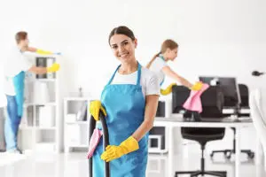 Professional cleaning company in a blue apron and yellow gloves cleaning a commercial business office