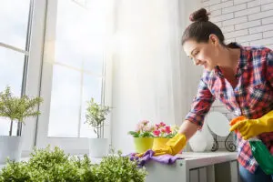 A homeowner in Springfield, IL holding a cleaning spray bottle and a purple cloth to clean the countertop of a kitchen or bathroom.