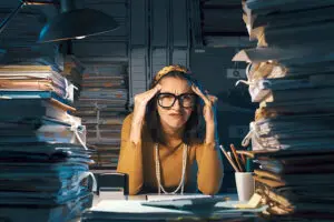 A woman sitting at her desk with a messy and cluttered office in Springfield, IL, and needing professional maid cleaning services.