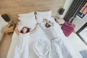 Two guests dressed in all white lying on a vacation rental bed and happy to be in a clean and relaxing vacation rental in Decatur, IL.