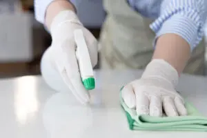 A residential homeowner wearing a blue and white striped shirt, white gloves, and spraying commercial chemicals on their hard surfaces in Decatur, IL.