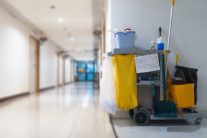Grey cleaning cart with yellow garbage bag placed next to a wall in a commercial business