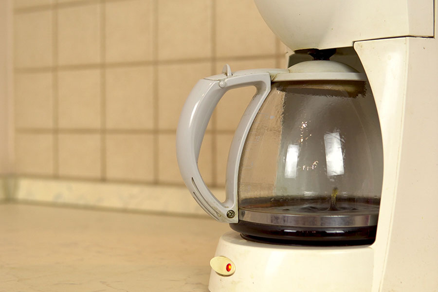 White coffee maker with dirty coffee pot needing to be professionally cleaned by a maid in Springfield, IL.