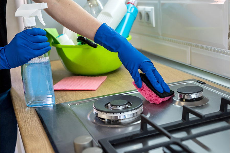A professional cleaner wiping down a stove with quality cleaning products in Springfield, IL.