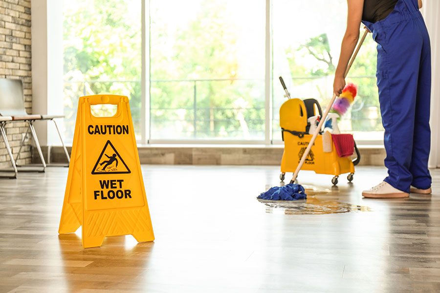 A professional janitorial service in Springfield, IL that is using a mop to clean the hardwood floors in an office setting.