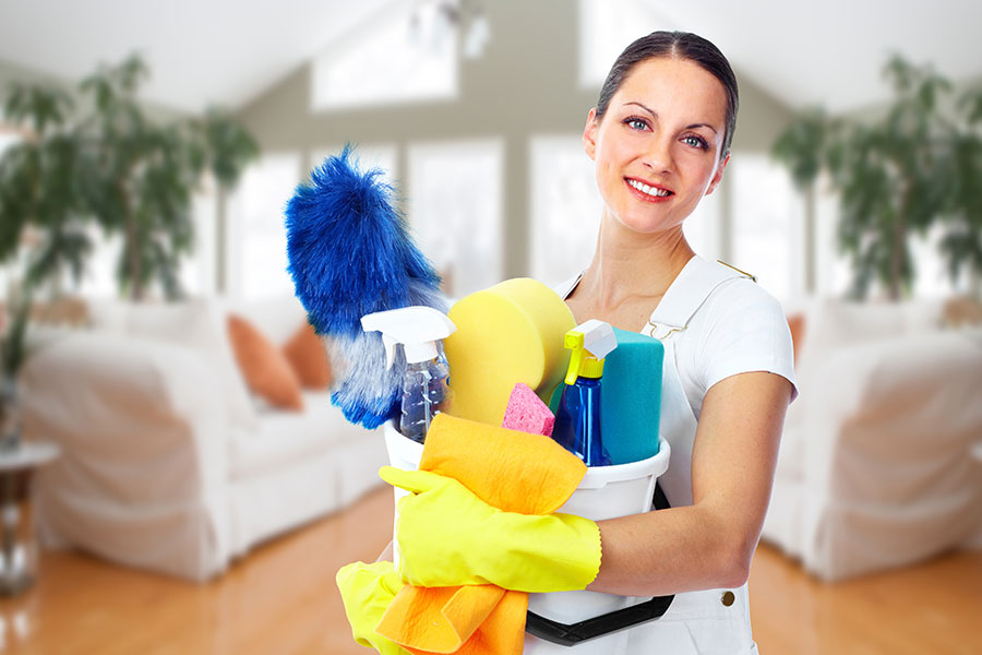 A professional cleaning maid in Springfield, IL holding various cleaning solutions in a home that requires weekly cleaning services.