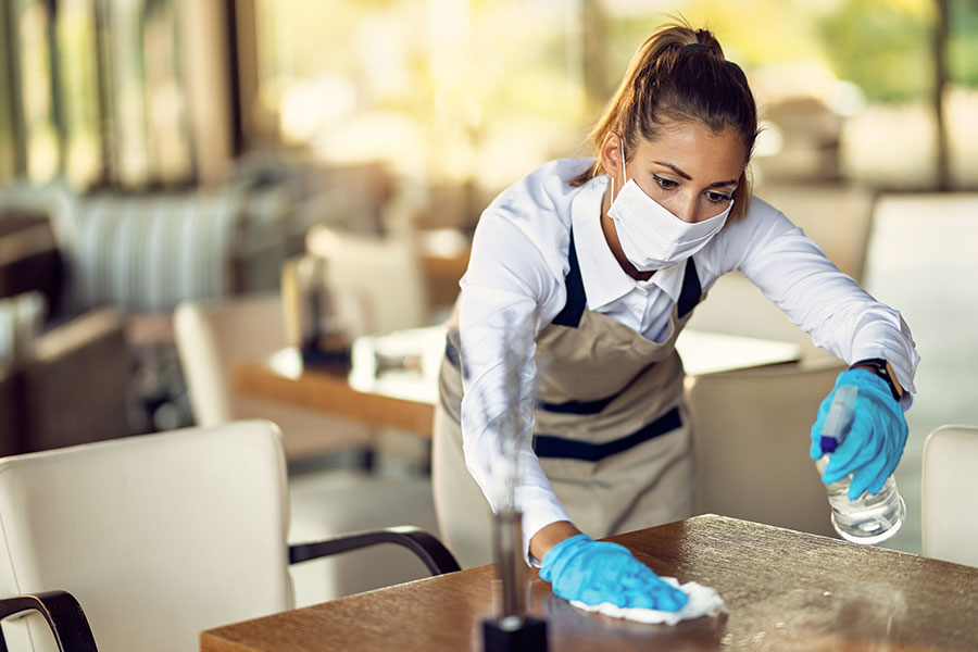 A professional maid using eco-friendly cleaning solutions to clean a table in a commercial business in Springfield, IL for seasonal cleaning.