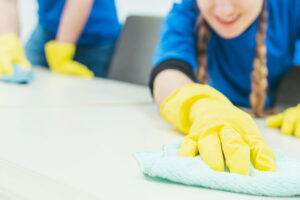Two professional cleaning staff members working for a commercial cleaning company in the Springfield, IL area. Both cleaning experts are wearing blue uniforms and yellow gloves.