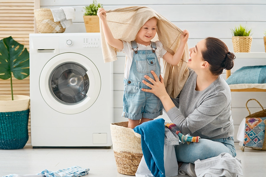 A mother and her child doing laundry together and having fun in a home in Decatur, IL.