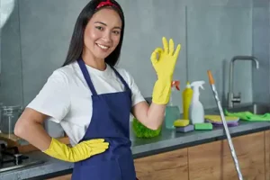 Golden Rule Cleaning & More—A young maid stands next to a countertop with cleaning supplies on it in a home in Springfield, IL, preparing to clean for allergies.