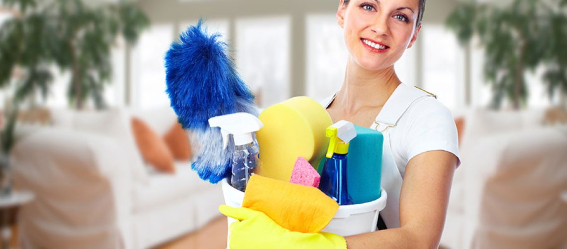 A professional cleaning maid in Springfield, IL holding various cleaning solutions in a home that requires weekly cleaning services.