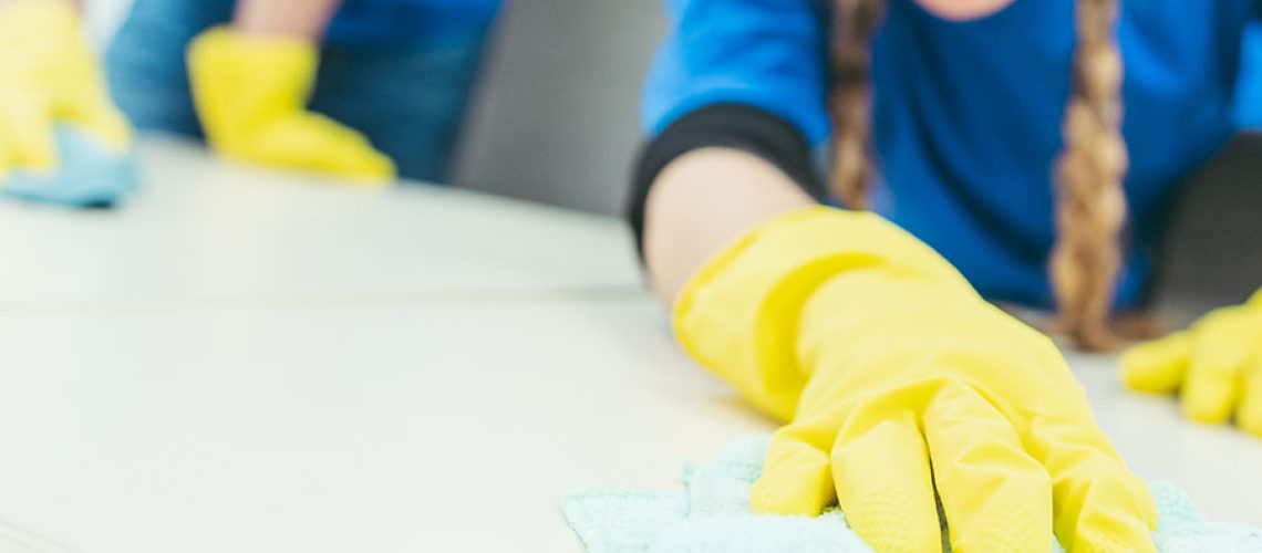 Two professional cleaning staff members working for a commercial cleaning company in the Springfield, IL area. Both cleaning experts are wearing blue uniforms and yellow gloves.